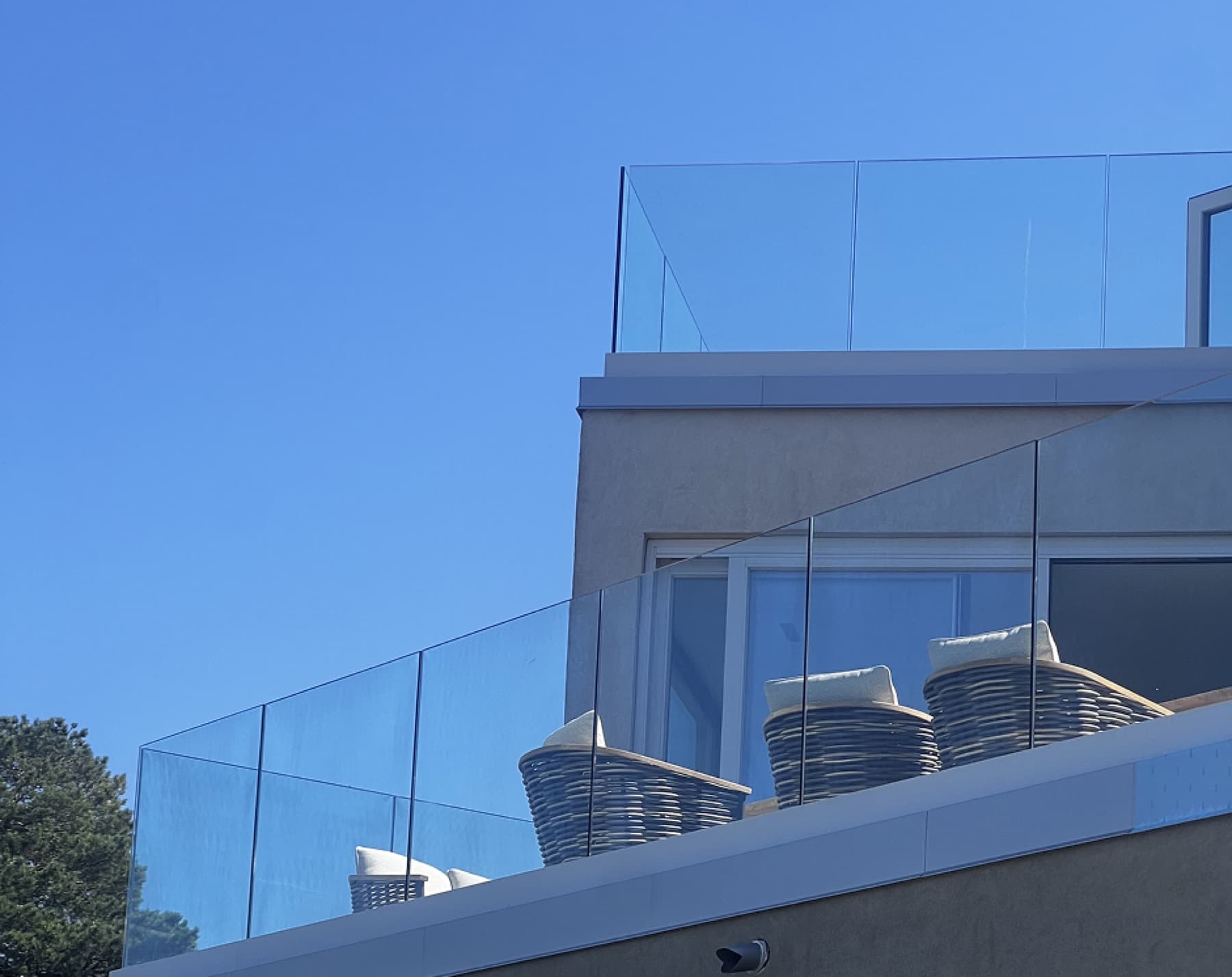 Glassrekkverk med kurvstoler mot blå himmel